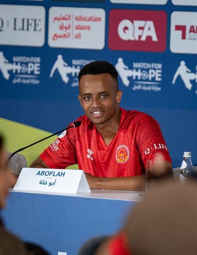 AboFlah answers questions at the Match for Hope press conference in Doha, a microphone and his nameplate in front of him